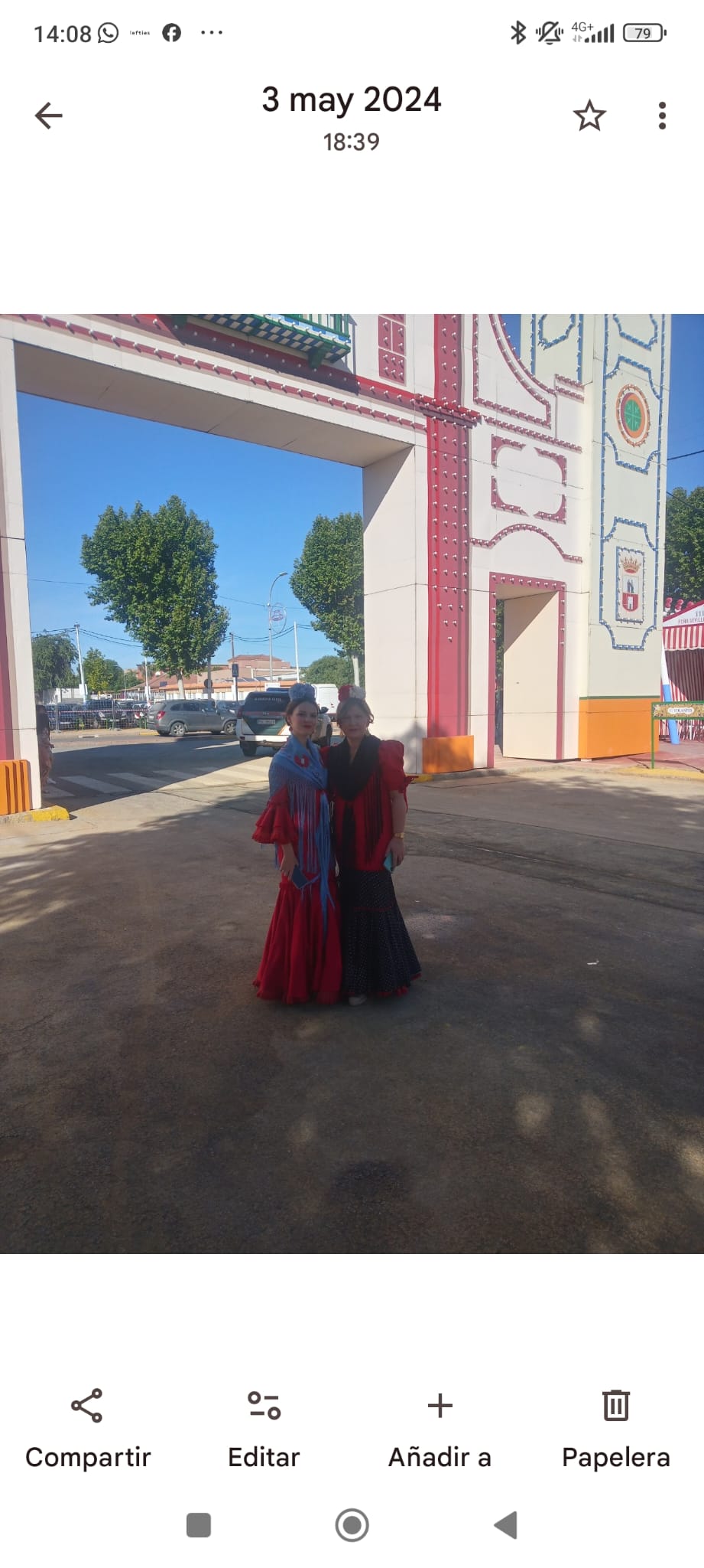 Dos personas con trajes de flamenca en la entrada de la feria